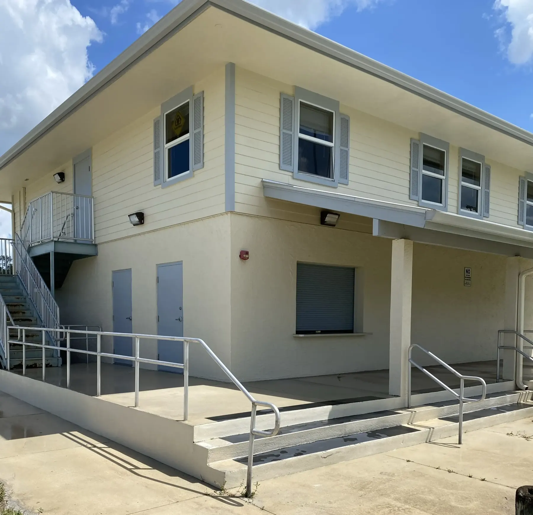 Two-story commercial building exterior with freshly painted cream siding and gray trim
