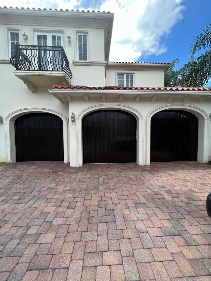 Cream stucco home with freshly painted black garage doors