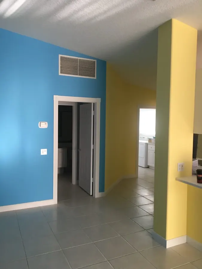 Interior hallway with a bold blue accent wall and a warm yellow adjoining room