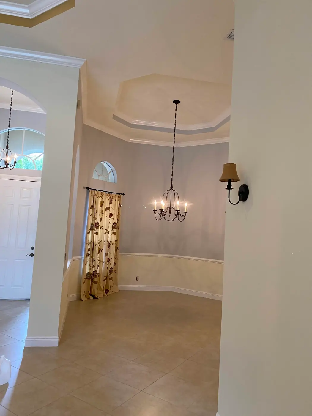 Formal dining room with gray walls, cream trim, and a wrought-iron chandelier