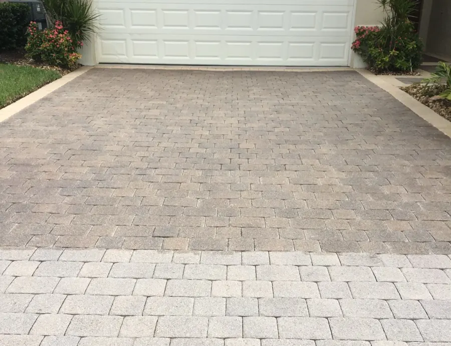 Tan paver driveway bordered by flowering landscaping