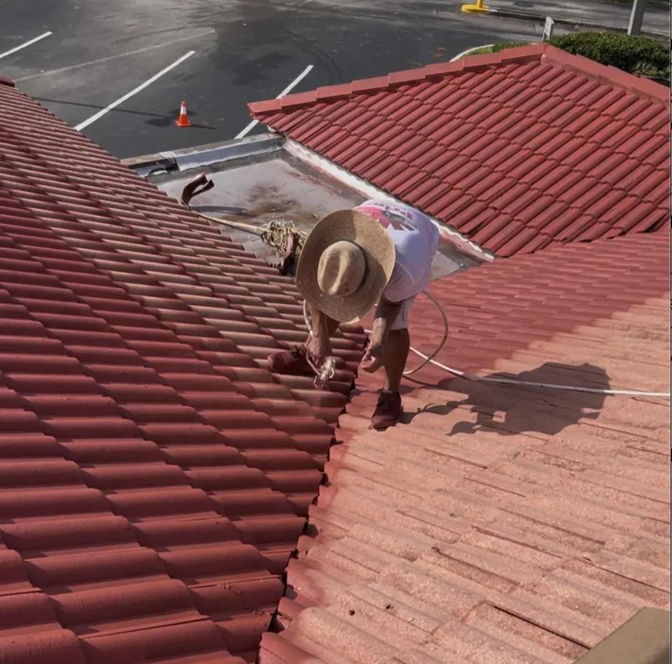 Prime Painting crew member applying roof coating on a commercial tile roof